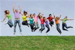 Colorfully attired teens jumping in a field