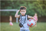 A Young Saluting Boy Holding A Soccer Ball On The Field